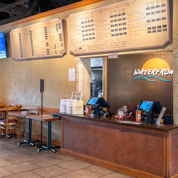 The interior of Waterfront Pizza shows a menu board, ordering counter, and dining tables.