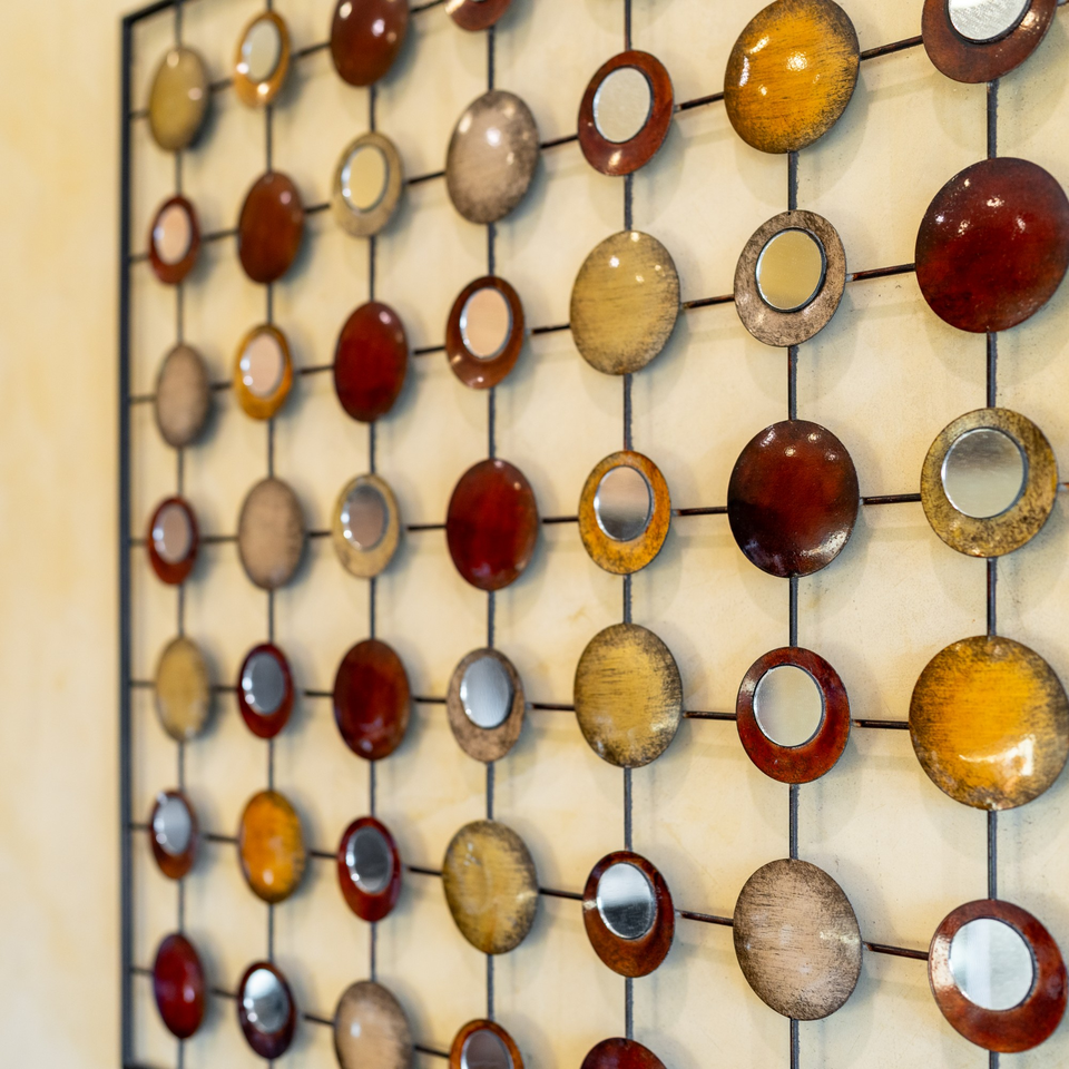 Decorative wall art with a grid of metallic circles in red, gold, and silver, some with mirrors.