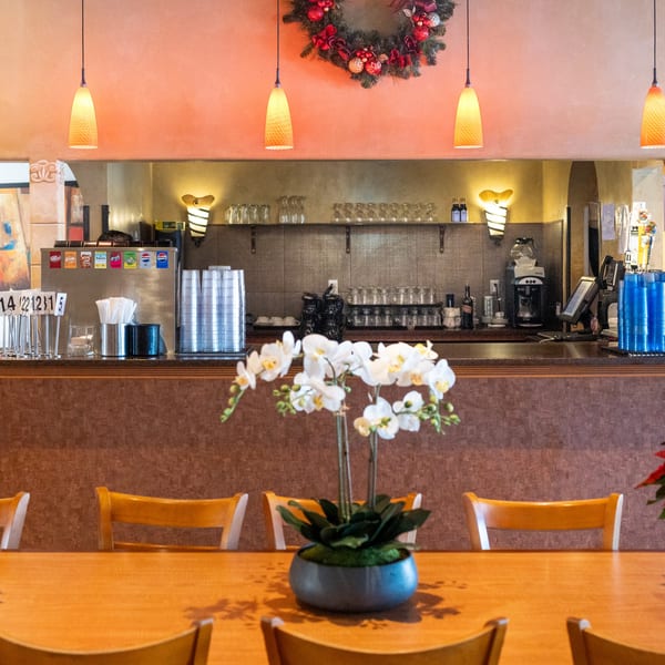 A Waterfront Pizza restaurant interior with a bar, soda fountain, and an orchid centerpiece on a wooden table.