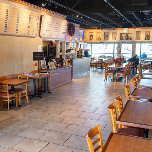 Spacious dining room at Waterfront Pizza with empty tables, a counter, and large windows.
