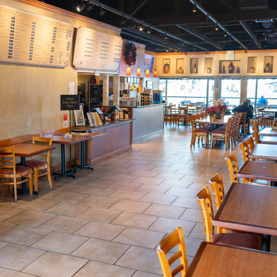 Spacious dining room at Waterfront Pizza with empty tables, a counter, and large windows.