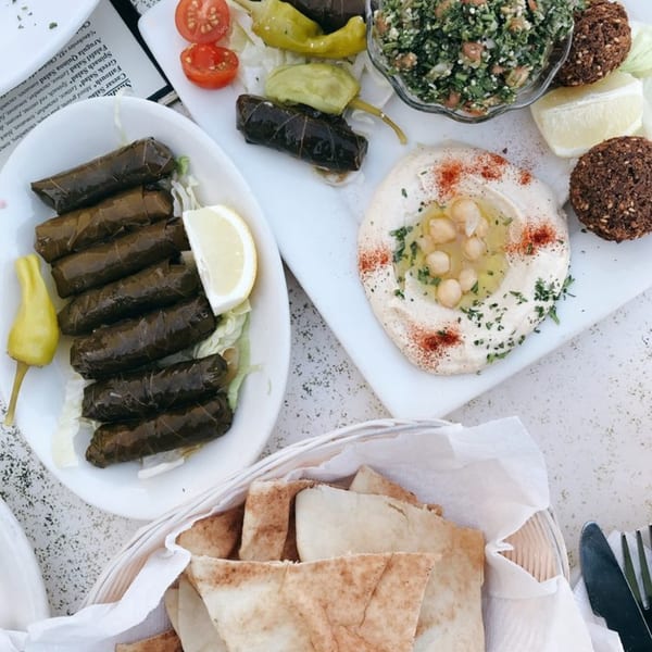 Overhead view of a Mediterranean platter with dolmades, hummus, falafel, tabbouleh, and pita bread.