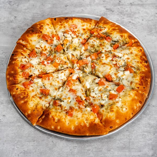 Waterfront Pizza's sliced pizza with diced tomatoes, feta cheese, and pesto on a metal pan.